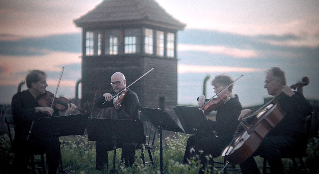 A string quartet plays in the grounds of Auschwitz. Still The Last Musician of Auschwitz
